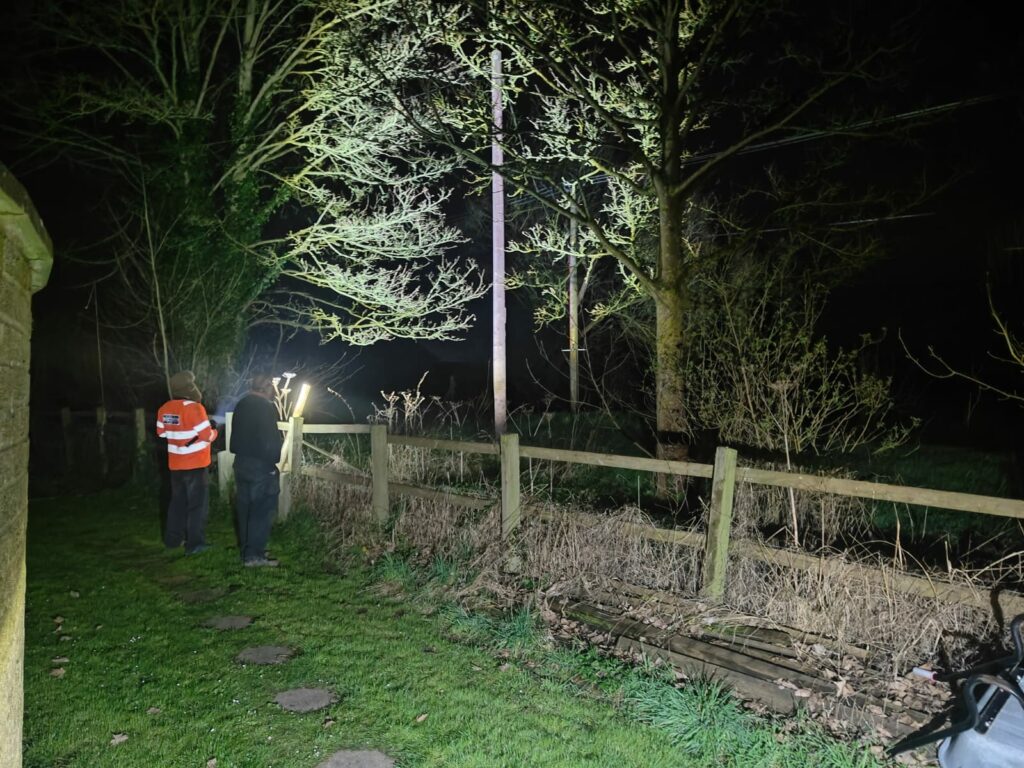 Linesmen examining an electricity pylon by torchlight.