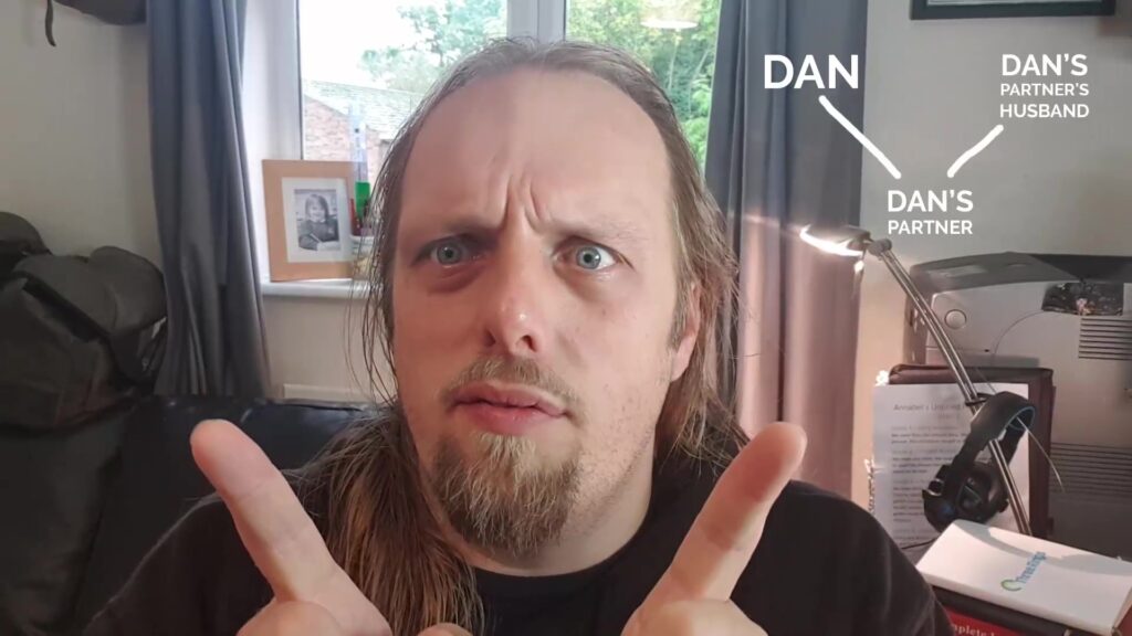 Framegrab from Dan's Howdymattic video showing him making a "V" shape with his fingers alongside a diagram of his V-shaped relationship.