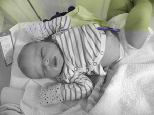 Forcep-marks still visible, the newborn takes an extended nap in a crib alongside Ruth's recovery-bed.