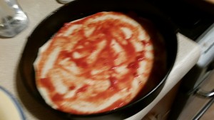 The first layer of pizza cake begins to be assembled in the tin.