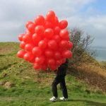 There's a struggle to control the balloons in the wind at the top of the hill