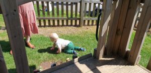One of the twins crawls around the play area.