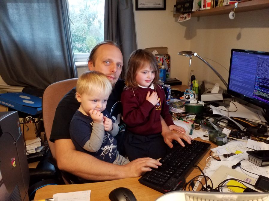 Dan using his computer with John and Annabel on his lap.