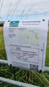 A "The Internet Was Here" sign explaining geohashing, attached to a gate using zip-ties.