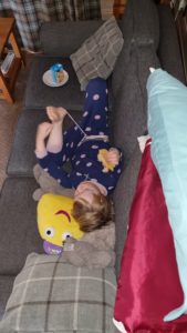 Lounging on the sofa with a CBeebie toy.