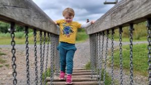 A boy concentrates hard as he crosses a wobbly bridge.