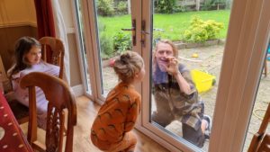 Children in pyjamas at a breakfast table greet Robin outside the patio doors.