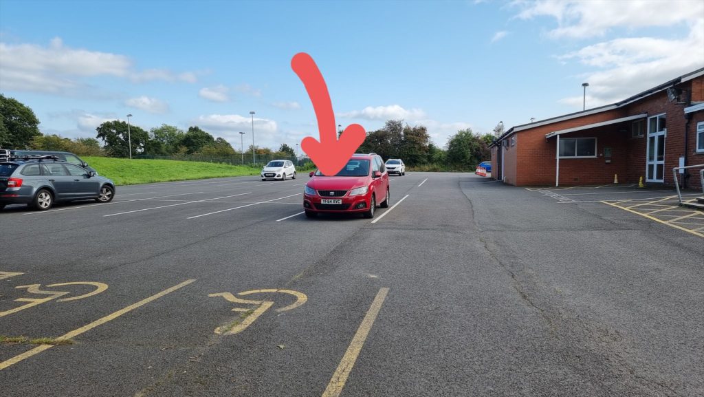 Car in car park with a large arrow pointing at it.