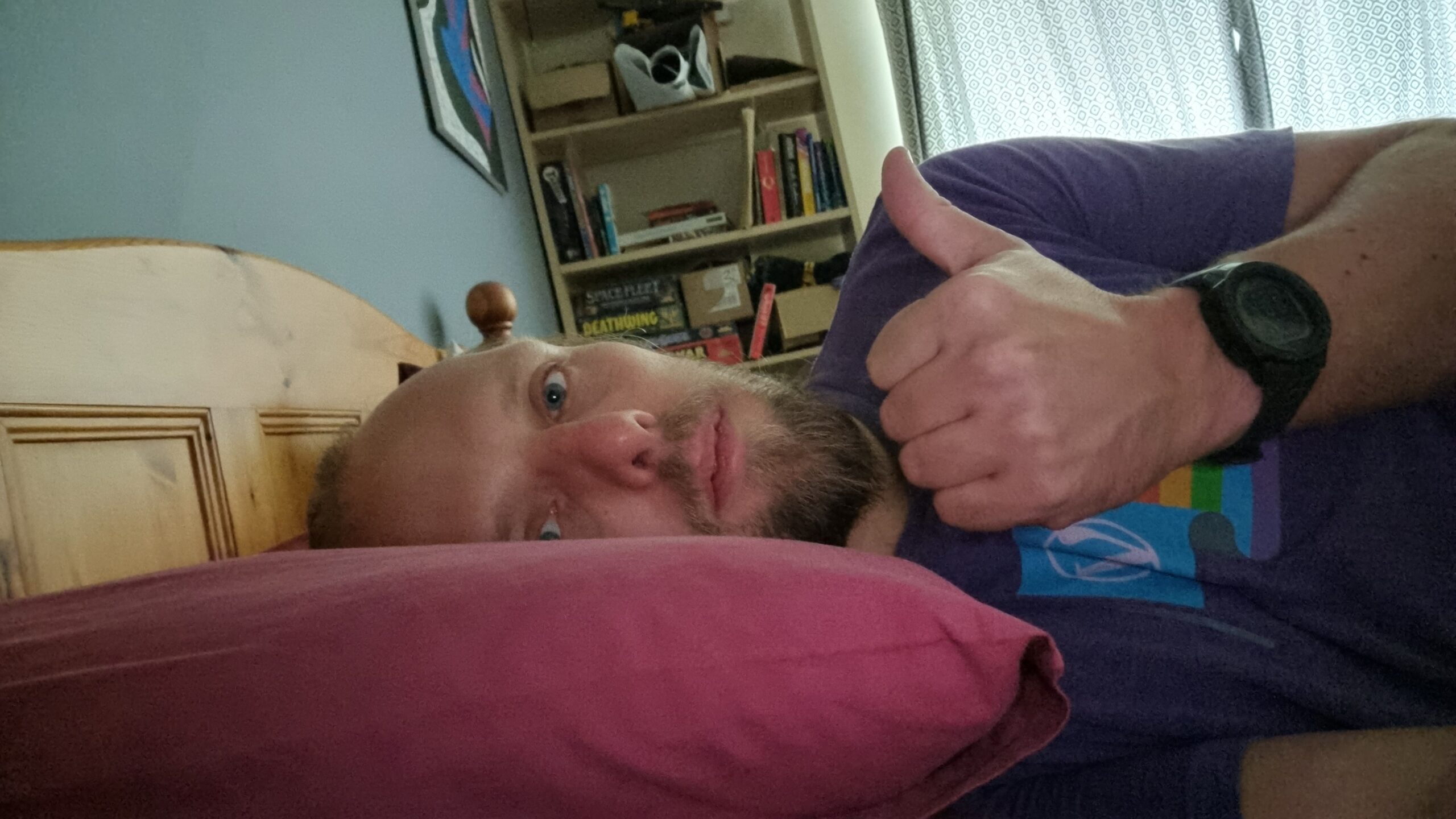 Dan lying in bed, giving a weak "thumbs up".