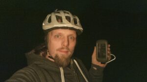 Dan, in the dark and wearing a cycle helmet, holds up a GPS receiver.