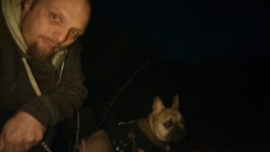 Dan takes a selfie in the dark; a French Bulldog looks confused in the background.