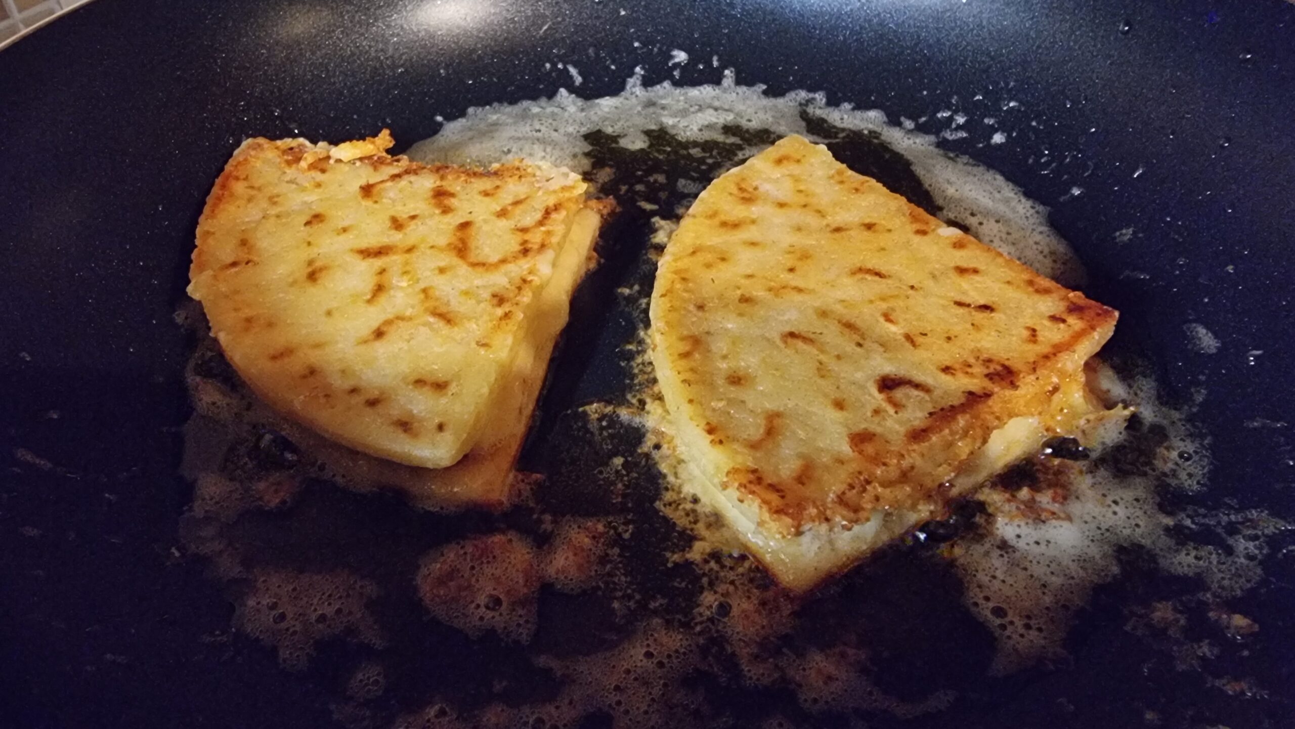 A pair of tattie scone quesadillas sizzling in a pan.