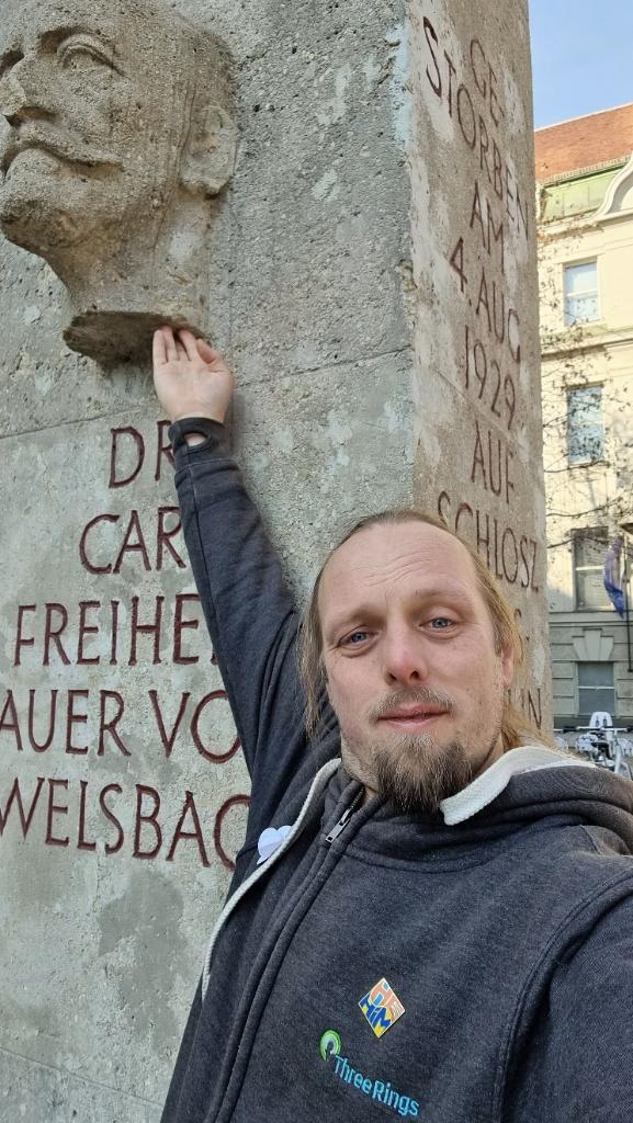 Dan reaches up to touch a bust of Dr. Carl Auer, Freiherr von Welsbach, Austrian chemist and engineer.