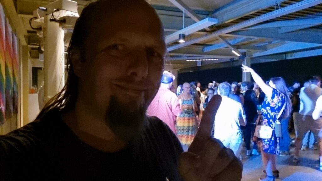 Dan, sweating, with an actively-used dancefloor in the background.