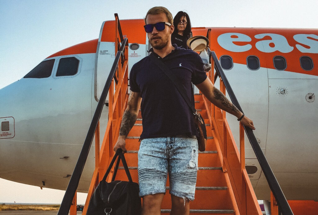 Two passengers - a man and a woman - disembark from an EasyJet plane via wheeled stairs.