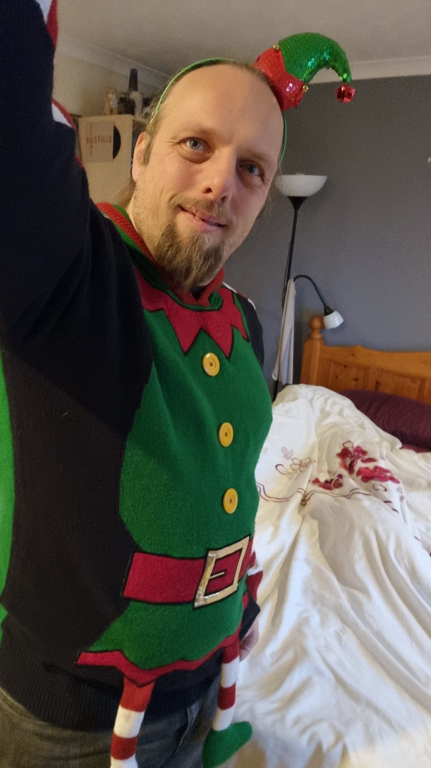 Selfie of Dan wearing an "elf costume" Christmas jumper and matching hat with bell.