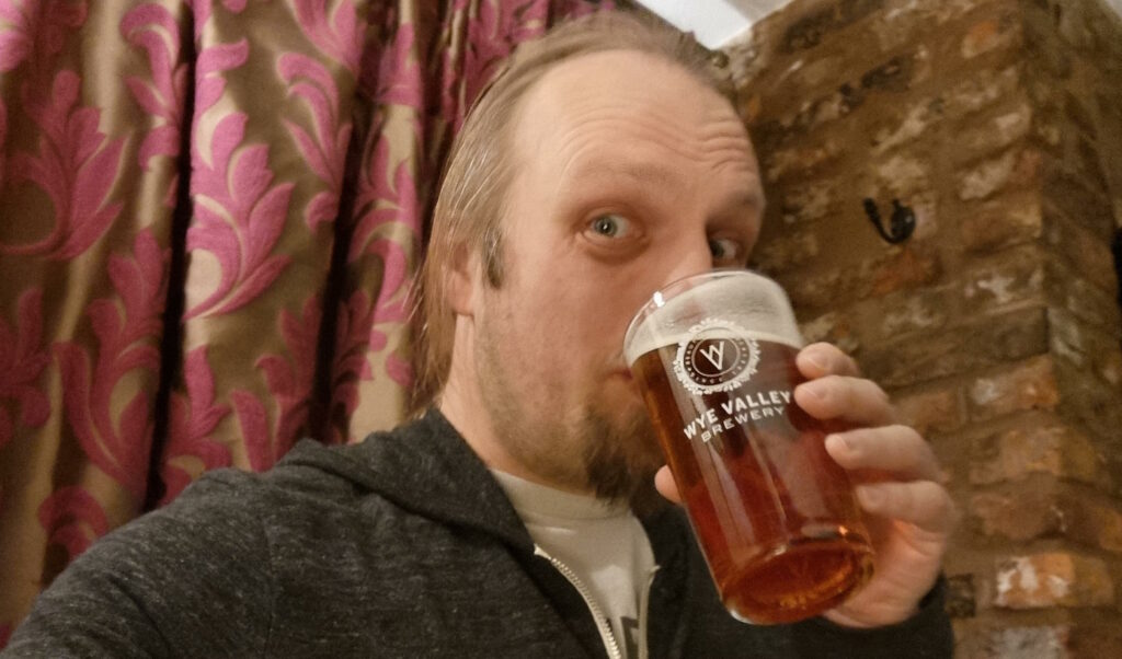 Dan drinking beer from a Wye Valley Brewery pint glass.