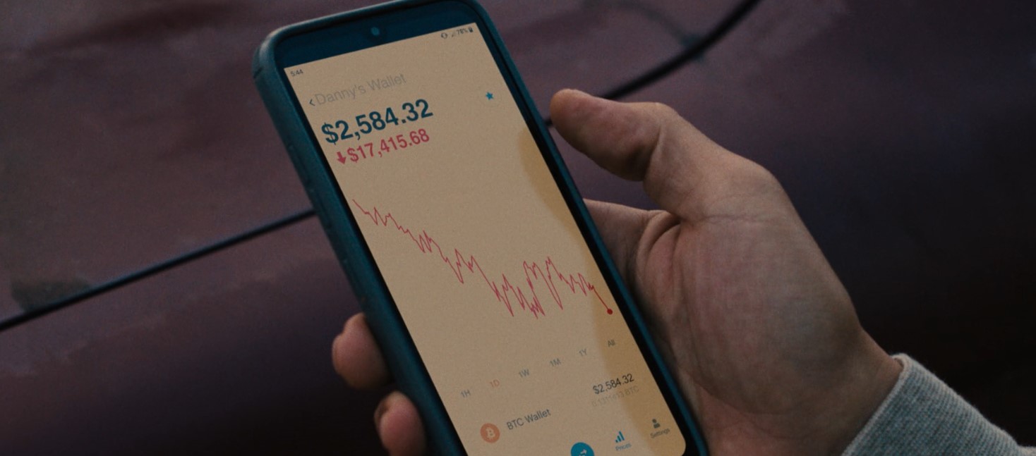 Screengrab from BEEF Series 1, Episode 1, showing a held mobile phone showing a Bitcoin wallet's value crashing by 87%