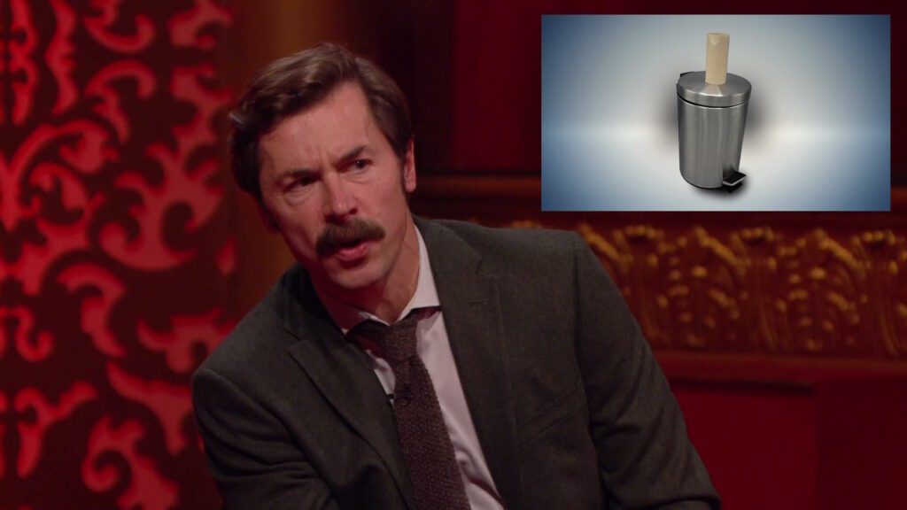 Composite screengrab from Taskmaster Season 11 Episode 4 (Premature Conker) showing Mike Wozniak talking about an empty toilet roll tube perched on top of a closed pedal bin (rather than having been put inside it).