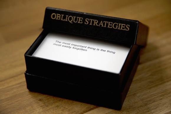 An open Oblique Strategies box with the face card showing: "The most important thing is the thing most easily forgotten".