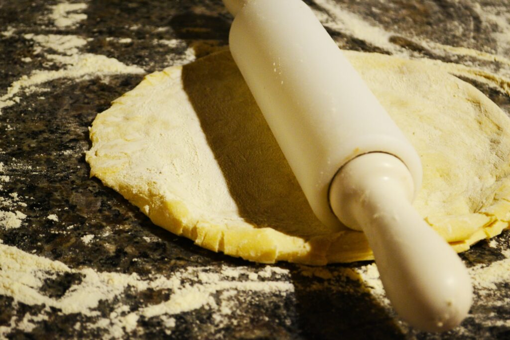 A circle of pizza dough on a worktop, a rolling pin atop it.