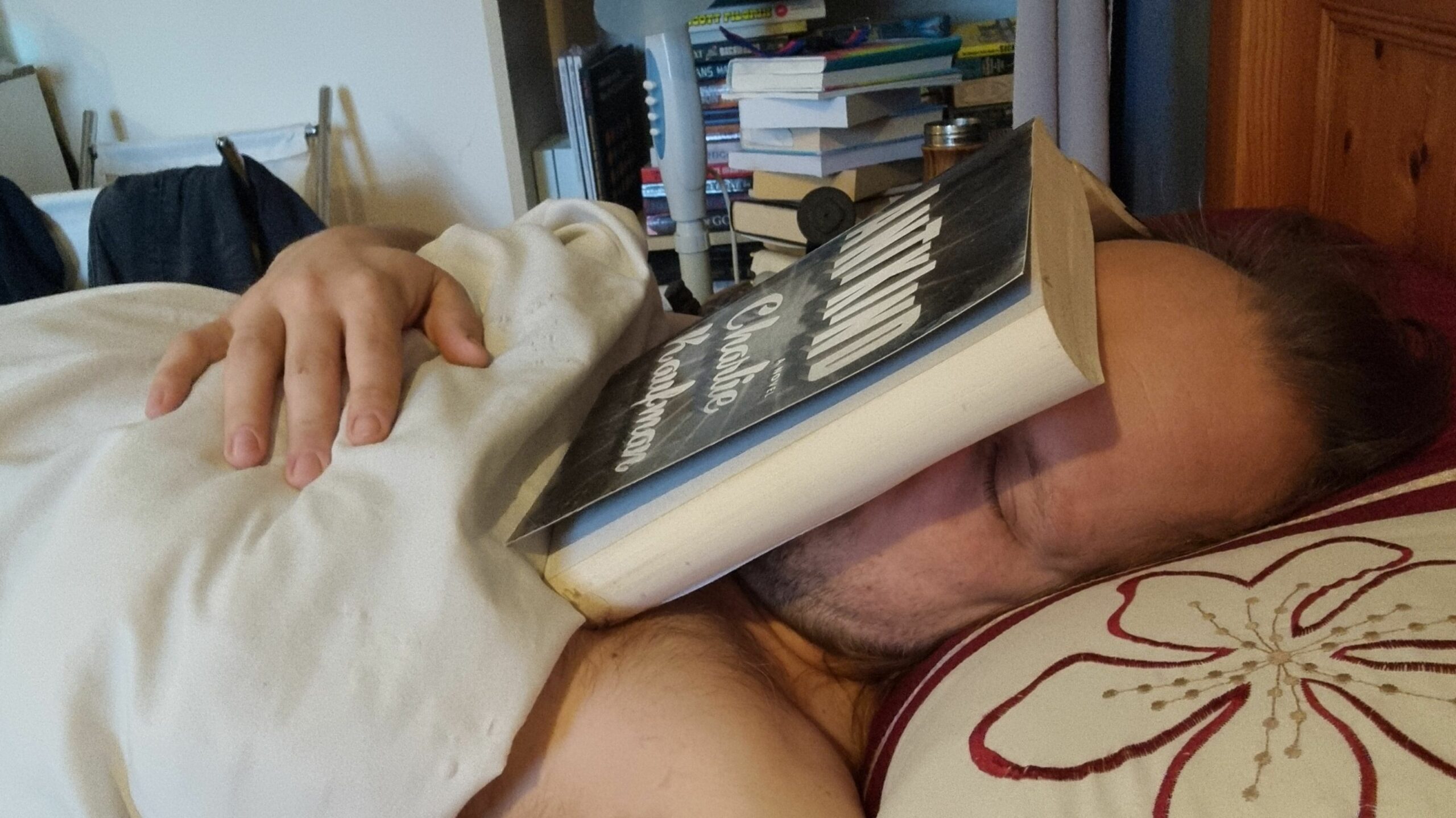 Photograph of Dan in bed, seemingly asleep with an open copy of Antkind on his face.