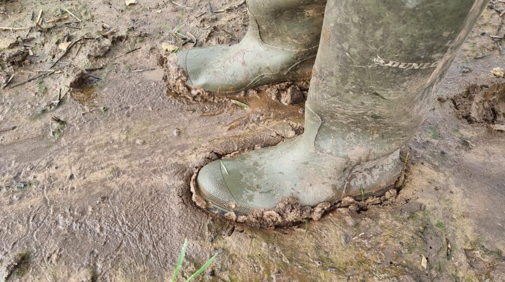 Green Wellington boots in deep sticky mud.