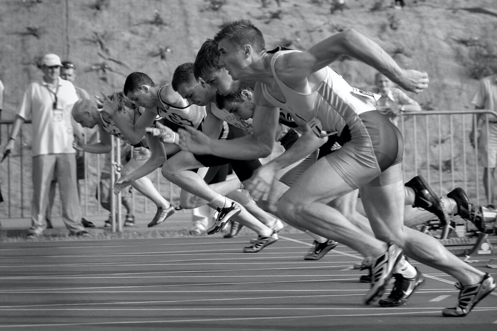 Monochrome photograph showing sprinters at the starting line.