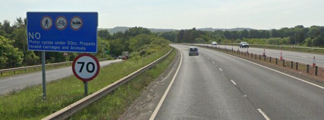 Google Street View photo from the A1 East of Edinburgh, showing a blue "No motor cycles under 50cc, moped,s invalid carriages and animals" sign alongside a 70mph sign.
