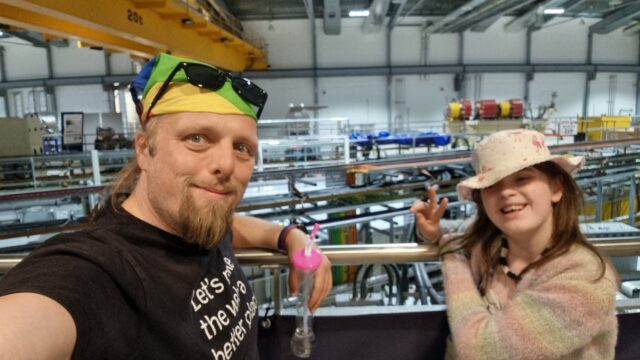 Dan with a child in front of beamlines coming out of the Diamond Light Synchrotron ring.
