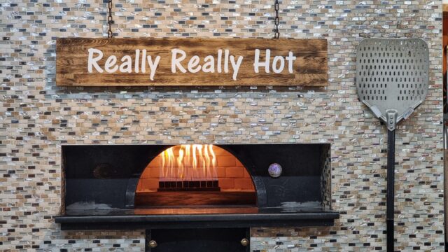 Commercial pizza oven with a decorative sign reading: really really hot.