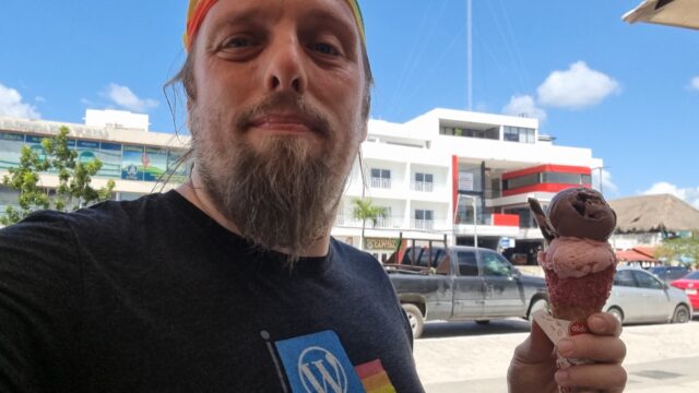 Dan, wearing a rainbow bandana, with an ornate ice cream cornet in a Mexican city.