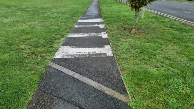 A footpath becomes a zebra crossing despite there being no road to cross, just a lawn (probably there USED to be a road).