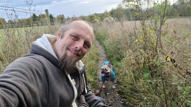 Dan crouches by his dog to take a selfie.