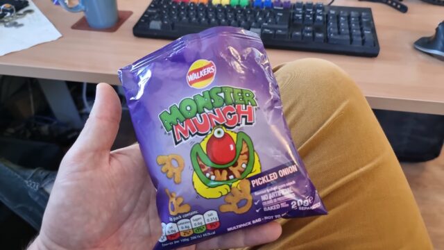 A packet of Pickled Onion Monster Munch, held in a hand.