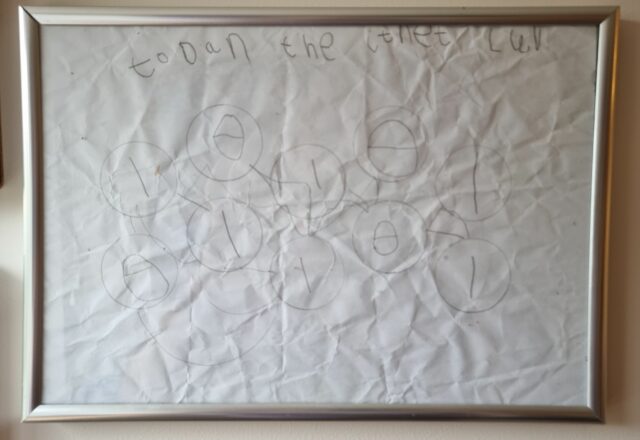 Framed child-drawn picture showing multiple circles, connected by lines, each with a number 0 or 1 in it.