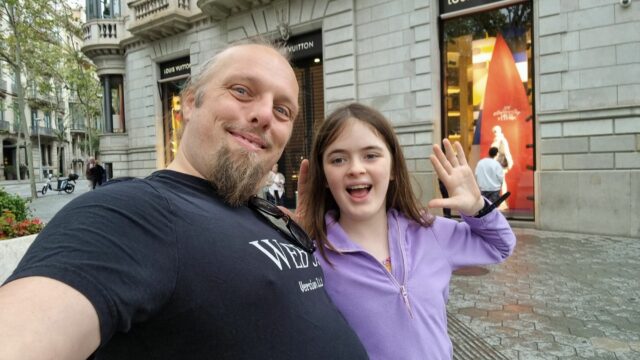 Dan and a child wave in a street.