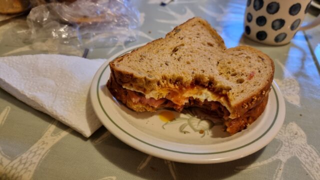 Bacon and egg sandwich on granary bread, with two bites taken out of it.