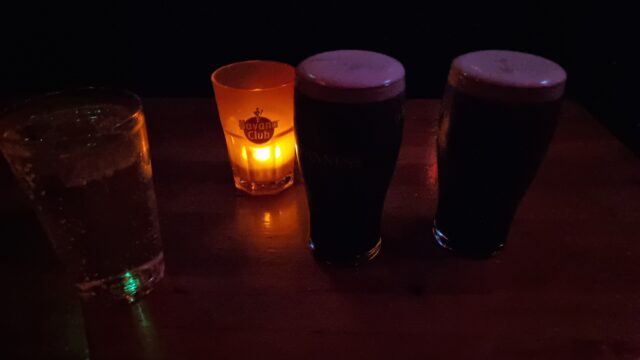 Two pints of Guinness on a candlelit table.