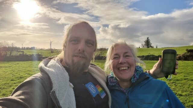 Dan and his mother grin in a grassy field.