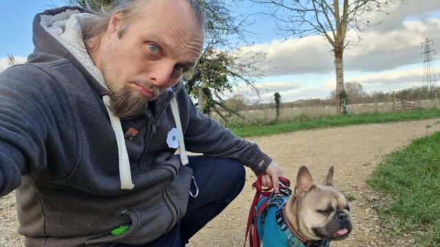 Dan and his dog on a footpath with a field in the background.