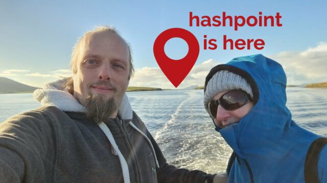 Dan and his mother ride on the back of a boat through a bay full of islands. In the distance, the distinctive shape of Clare Island can be seen, jutting out from the sea, and to the left of it a red pin is superimposed upon the image with the message 'hashpoint is here'.