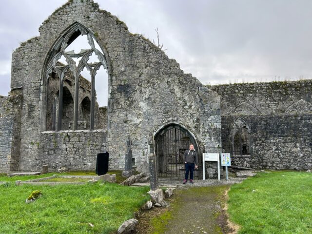 Dan stands in front of a ruined priory.