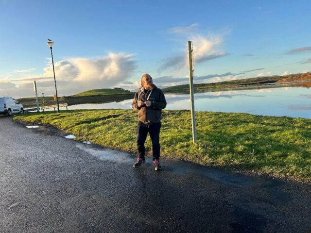 Dan stands near the sea.