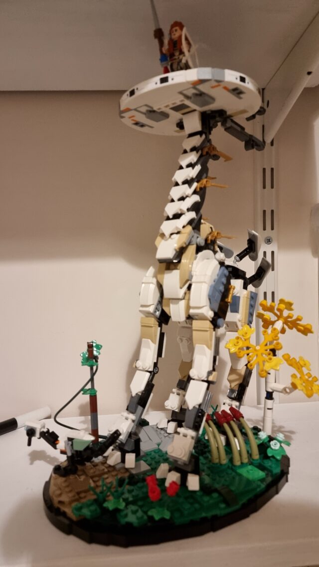 Lego model of a Tallneck from videogame Horizon: Zero Dawn/Forbidden West, with minifigure of protagonist Aloy standing atop its head.