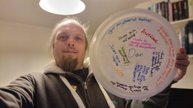 Dan holding a plate containing his name and a collection of compliments, listed in the full post.