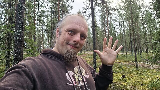 In a spruce forest, Dan waves.