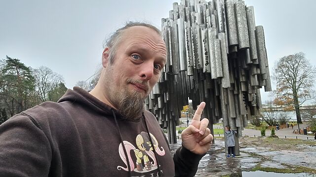 Dan points to an organic, tree-like sculpture formed from dozens of upright pipes.