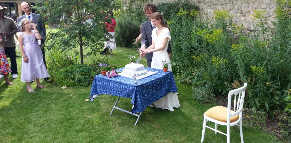 Matthew and Katherine cut the cake in the garden of the Quaker Meeting House.