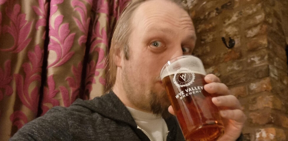 Dan drinking beer from a Wye Valley Brewery pint glass.